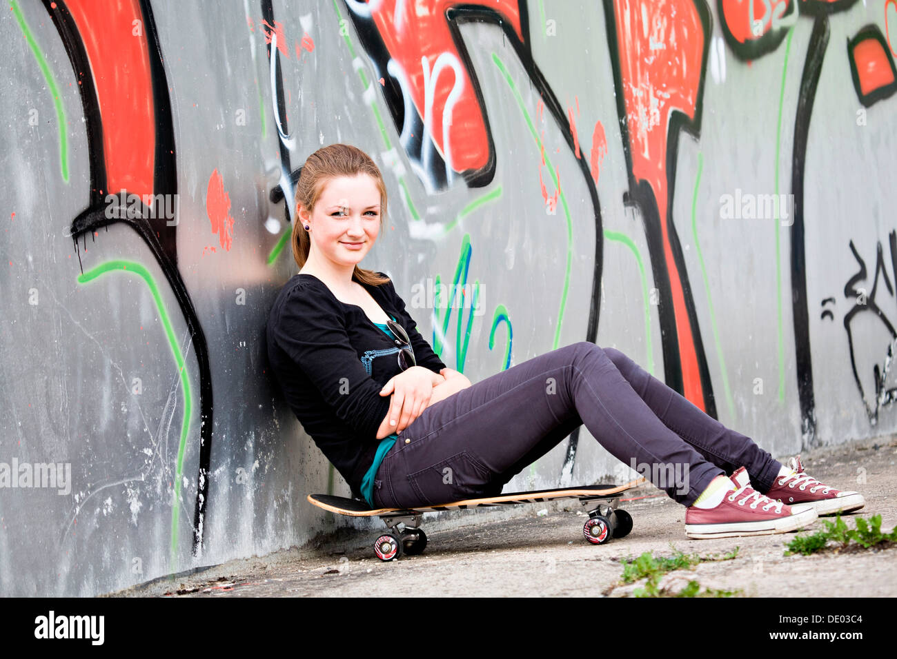Teenage girl with skateboard dans un environnement urbain Banque D'Images
