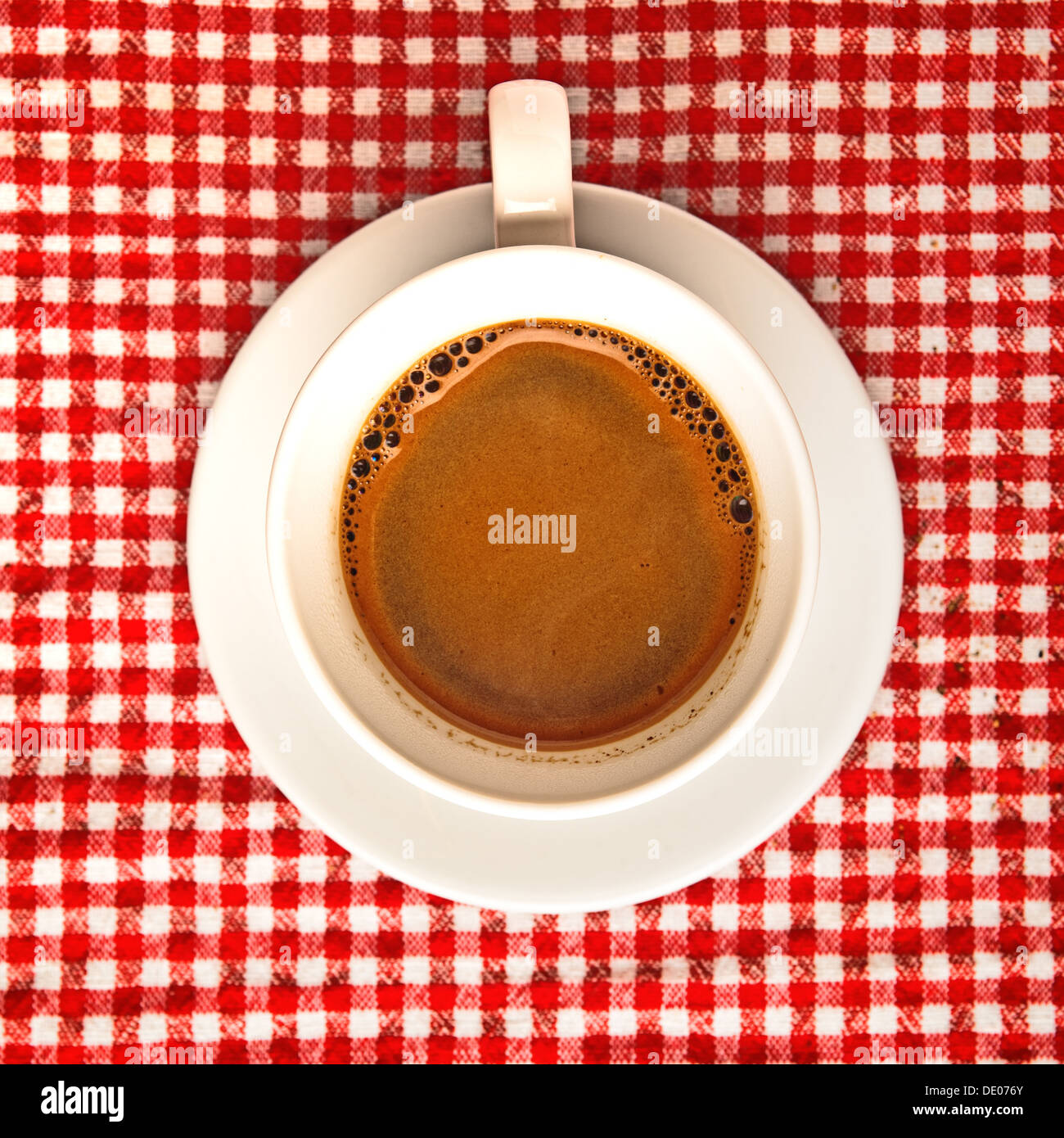 Tasse de café sur la table. Tasse de café noir à damier rouge et blanc de l'ob, nappe en arrière-plan. Banque D'Images
