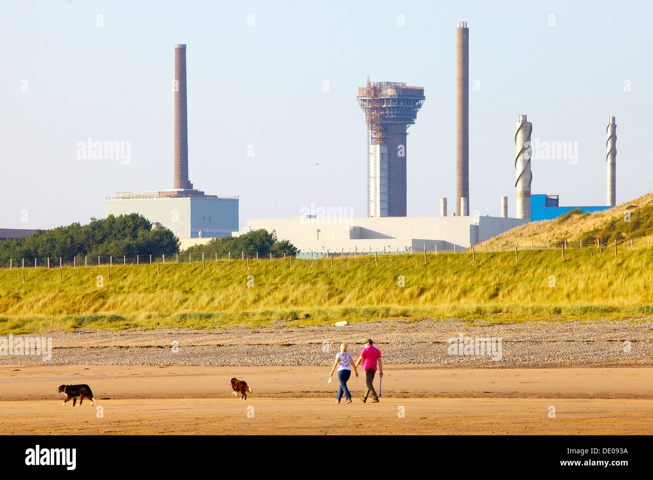 Centrale nucléaire de Sellafield avec un couple promènent leurs chiens sur le bord de la mer en face de Cumbria England Royaume-Uni Banque D'Images