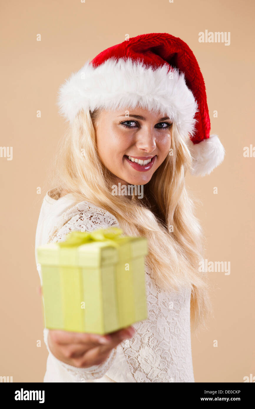 Smiling blonde woman wearing a Santa hat et présentation d'un don Banque D'Images