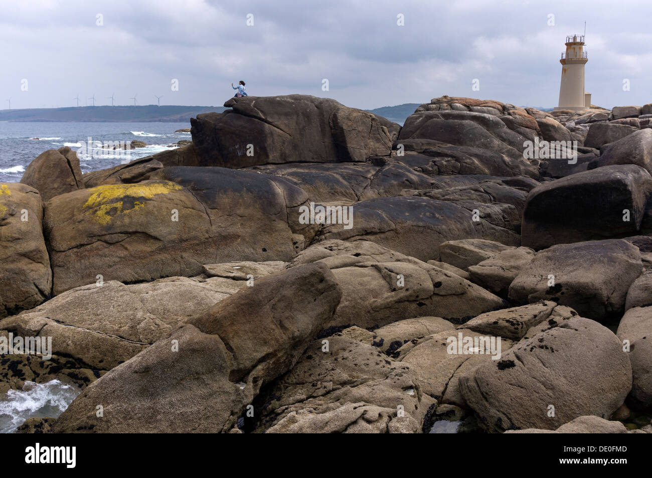 Une femme regardant la mer assis sur les falaises de la côte de la mort à Muxia. Banque D'Images