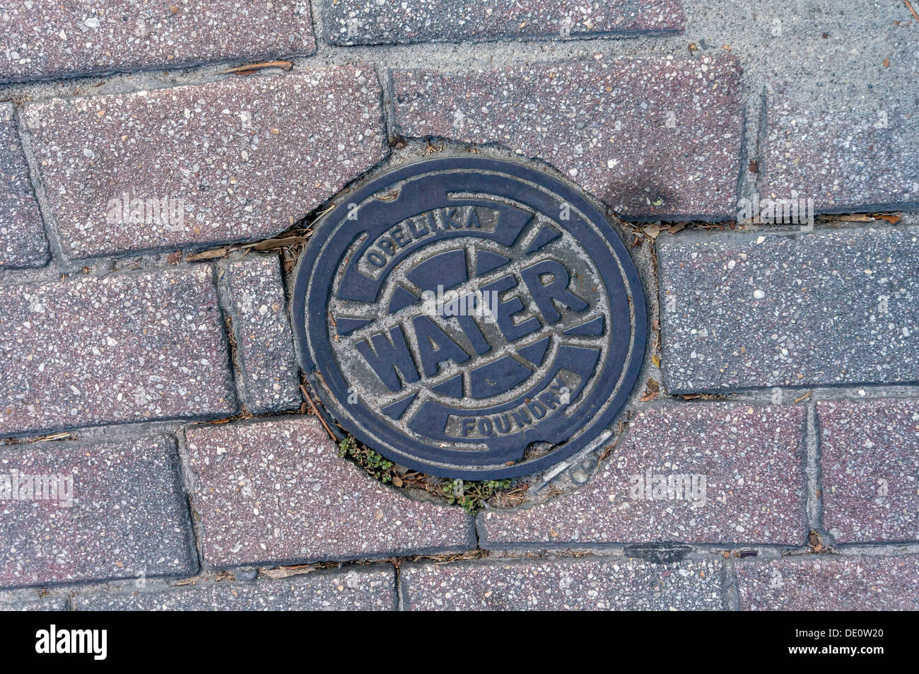 Entreprise de services publics de l'eau rue du tuyau en fonte nettoyage accès forgés par Opelika Foundry situé dans les pavés de brique. Banque D'Images