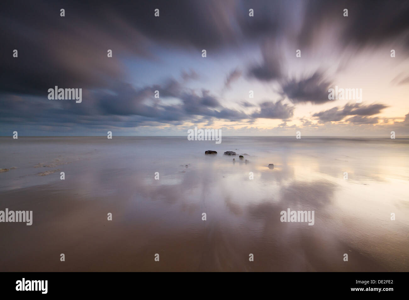 Vagues se brisant sur une plage rocheuse pendant le coucher du soleil Banque D'Images