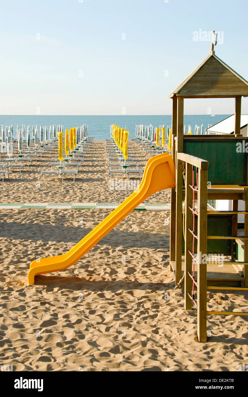 Début de saison, aire de jeux, toboggan, fermé des parasols sur la plage de sable, l'Adria, Caorle, Province de Venise, Vénétie, Italie, Europe Banque D'Images