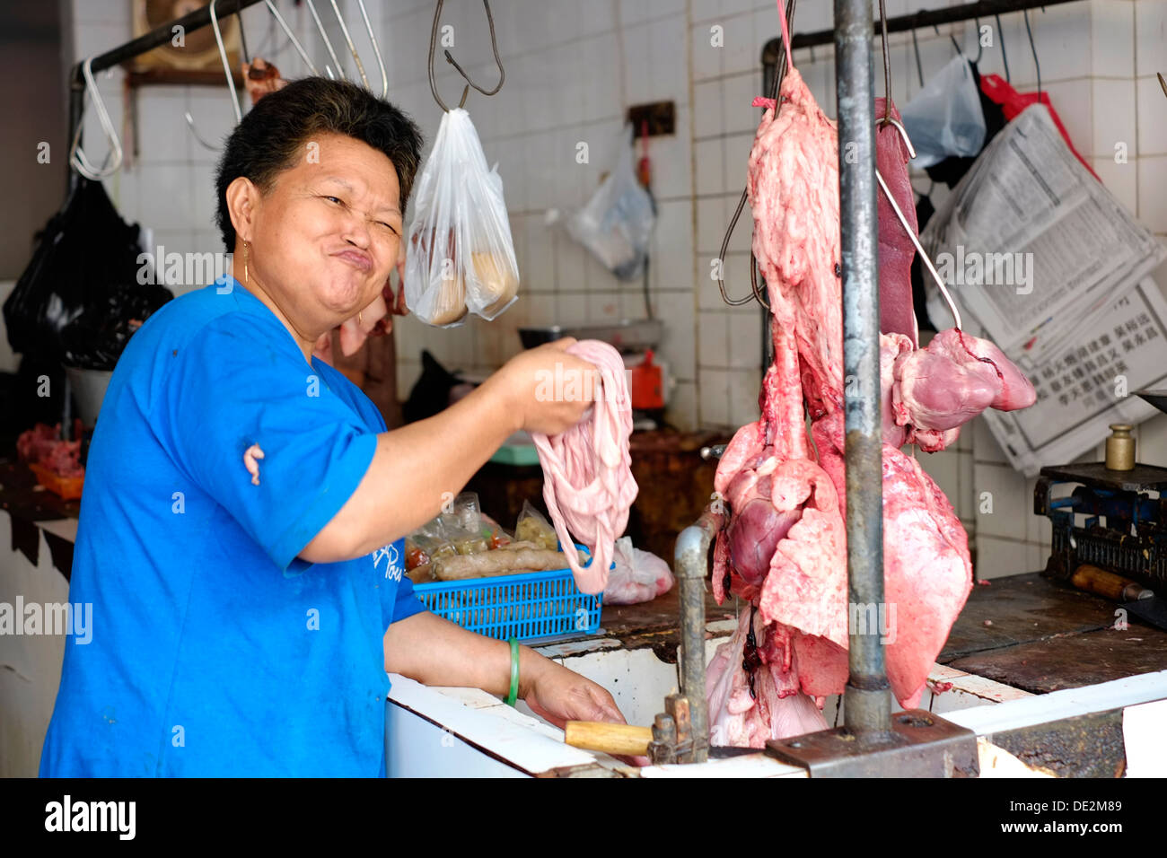 Femme à caractère chinois avec une poignée d'abats de porc prépare dans une boutique de bouchers à malang java indonésie Banque D'Images
