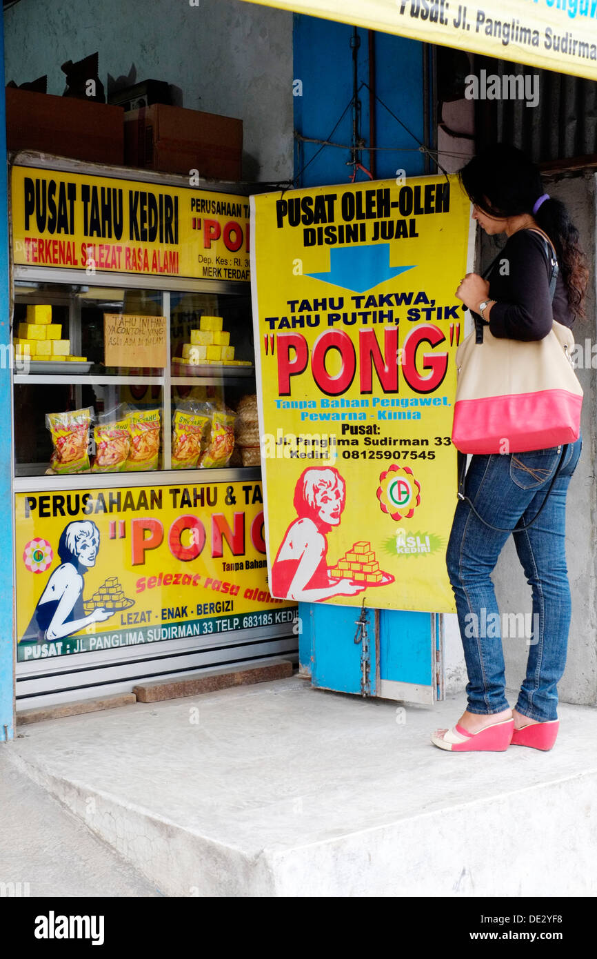 Femme debout par magasin de vente local le tofu avec le nom de marque de commerce de pong medan indonésie java Banque D'Images