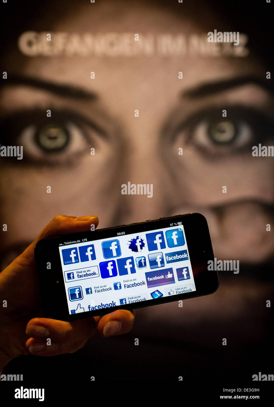 ILLUSTRATION - Un homme est titulaire d'un smartphone affichant le logo de Facebook à l'avant d'une plaque-étiquette 'lecture' pris dans le filet à la cyberintimidation International Congress à Berlin, Allemagne, 11 septembre 2013. La conférence sur la cyberintimidation comment prévenir l'intimidation sur l'internet et la façon d'aider les utilisateurs d'Internet d'intimidation. Photo : Hannibal Banque D'Images