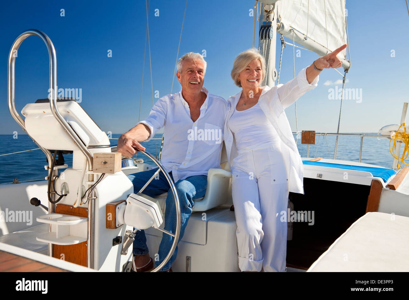 Un heureux couple au volant d'un voilier sur une mer bleu calme Banque D'Images