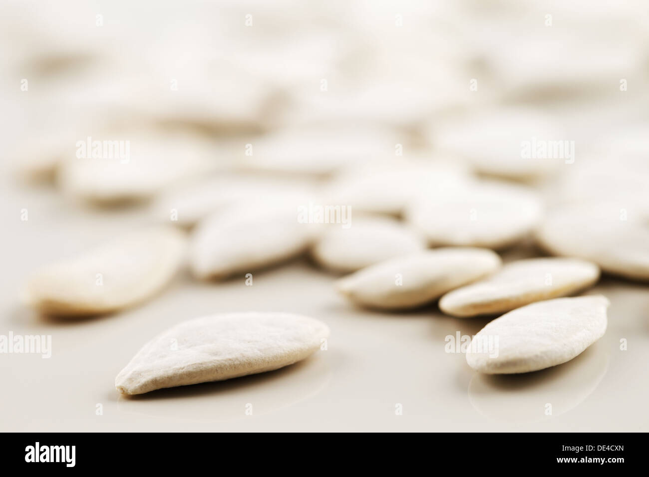 Les graines de citrouille blanc biologique tourné de manière abstraite sur un fond blanc. Banque D'Images