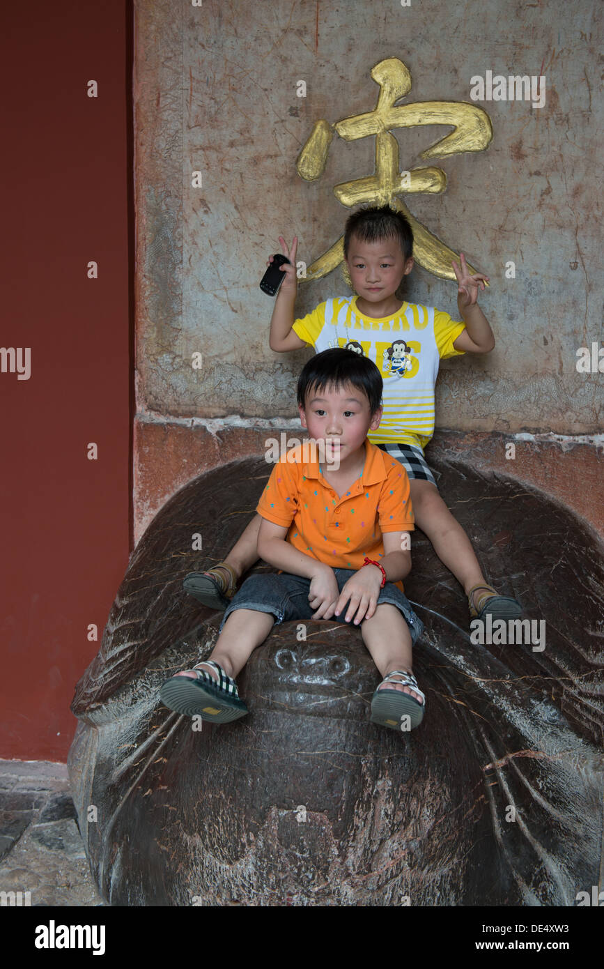 Les Tombeaux des Ming, Nanjing, Chine. Les enfants jouant sur la tortue maintenant l'Empereur Kangxi stèle à la tablette Hall. Banque D'Images