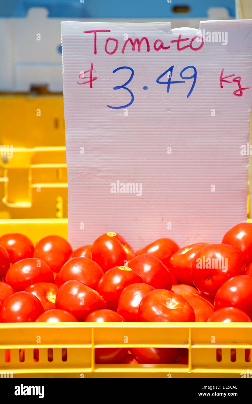 Les tomates dans un panier jaune avec une étiquette de prix Banque D'Images