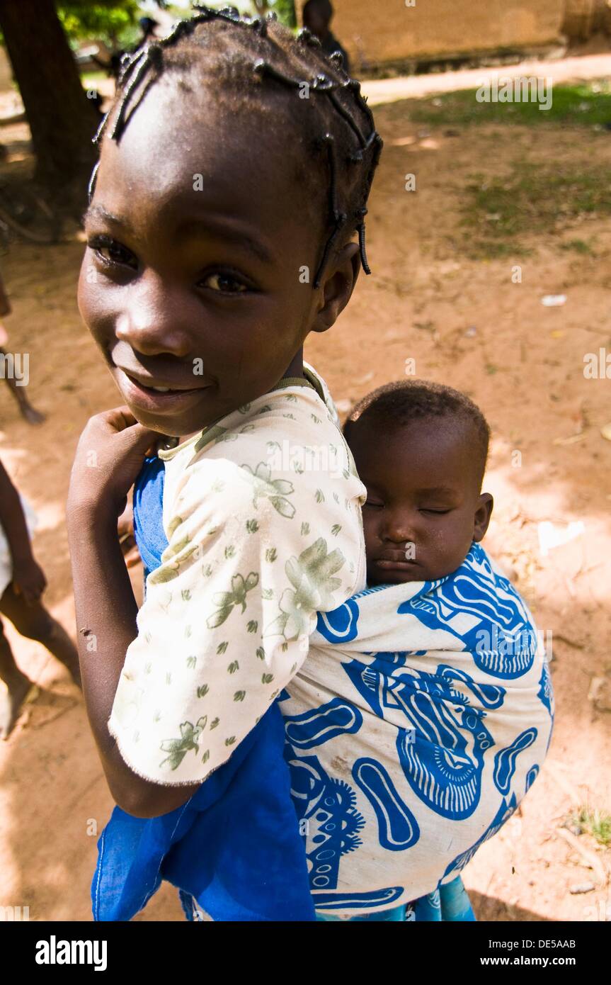 Une Fille Mignonne Du Burkina Faso D Enfant Portant Son Bebe Sur Son Dos Photo Stock Alamy