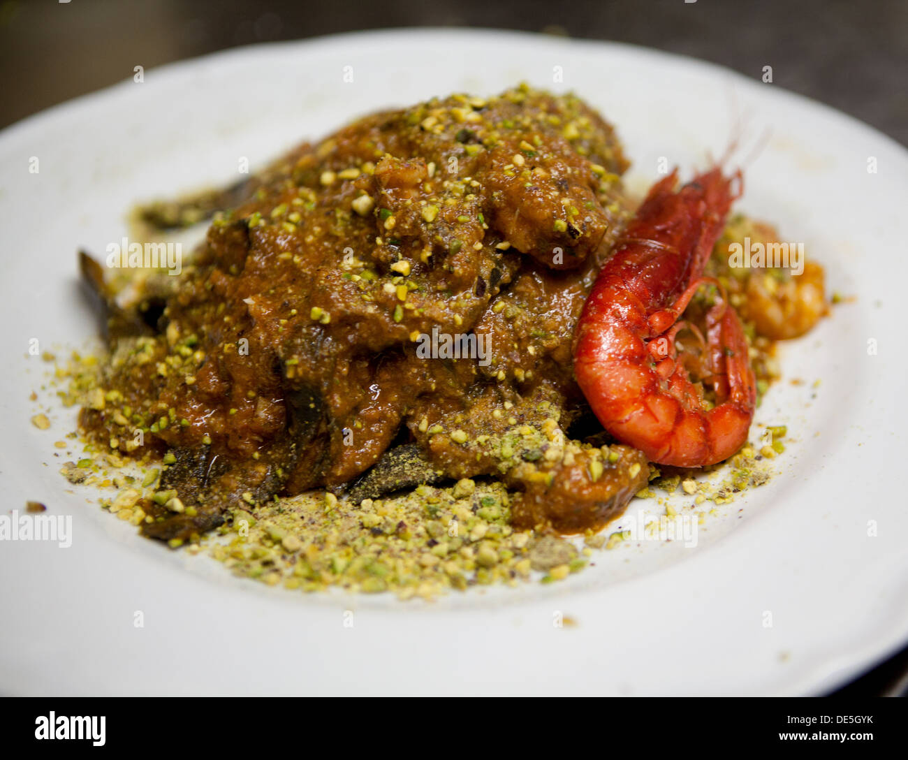 Un roi noir pâtes aux tomates, crevettes avec sauce Pistache servie sur une assiette blanche. Banque D'Images