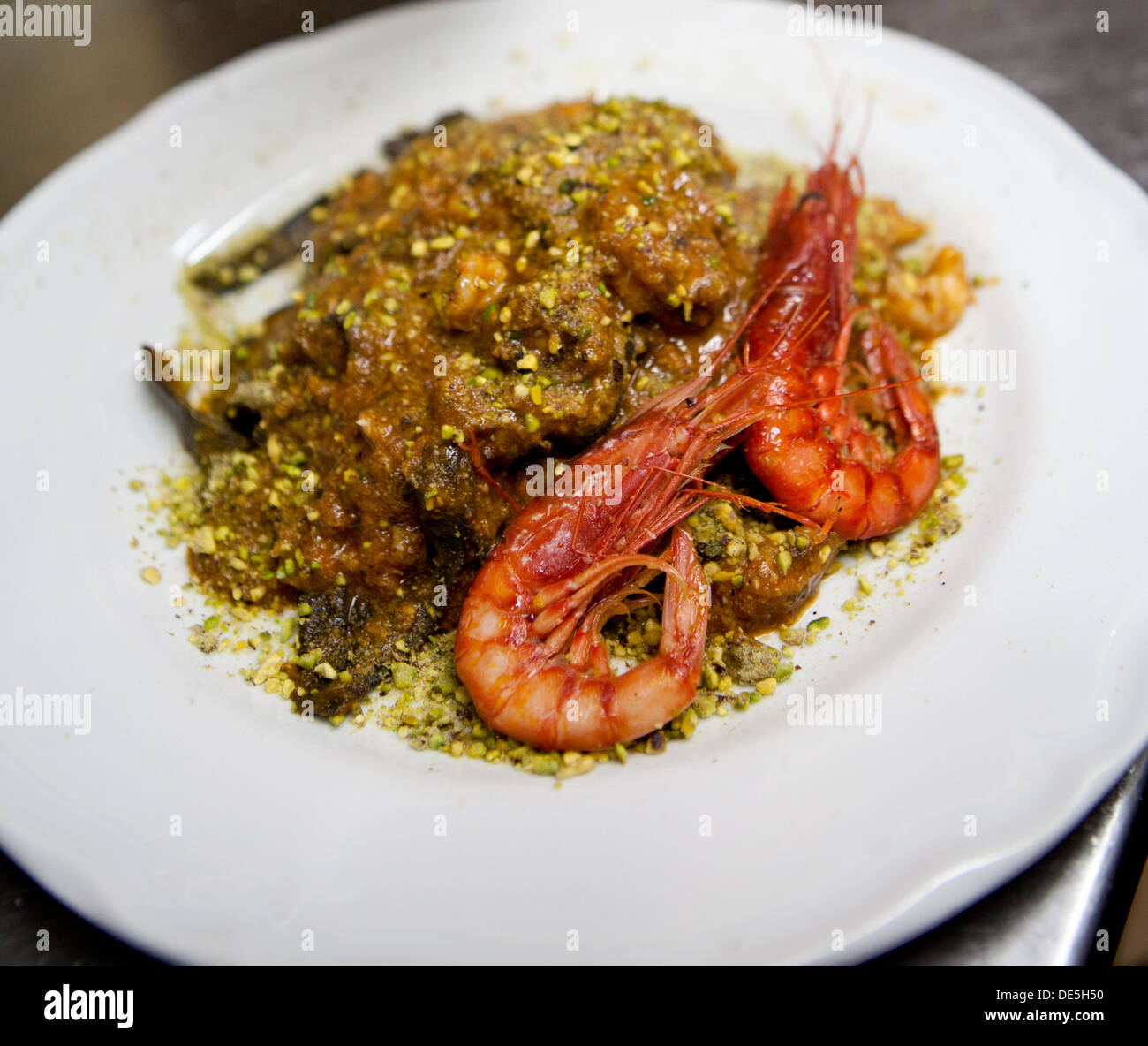 Un roi noir pâtes aux tomates, crevettes avec sauce Pistache servie sur une assiette blanche. Banque D'Images