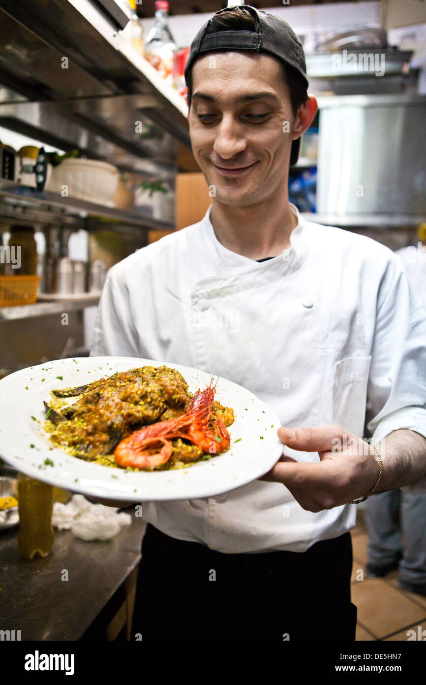 Un chef cuisinier prépare une pâte noir et plat de langoustines dans une cuisine de restaurant. Banque D'Images