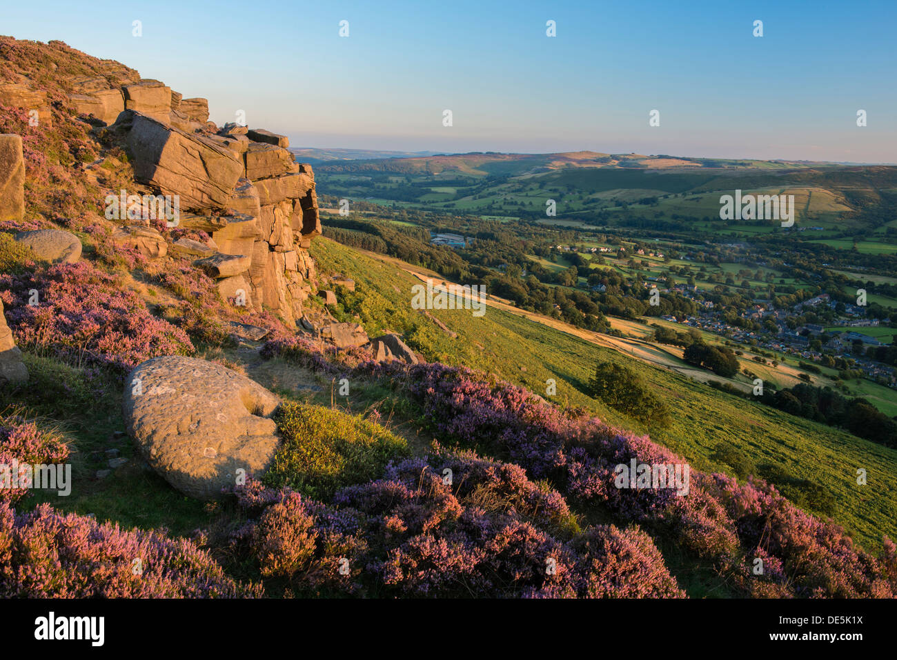 Heather entoure une meule sur Bamford Edge avec le village de Bamford ci-dessous. Peak District, Derbyshire, Angleterre Banque D'Images
