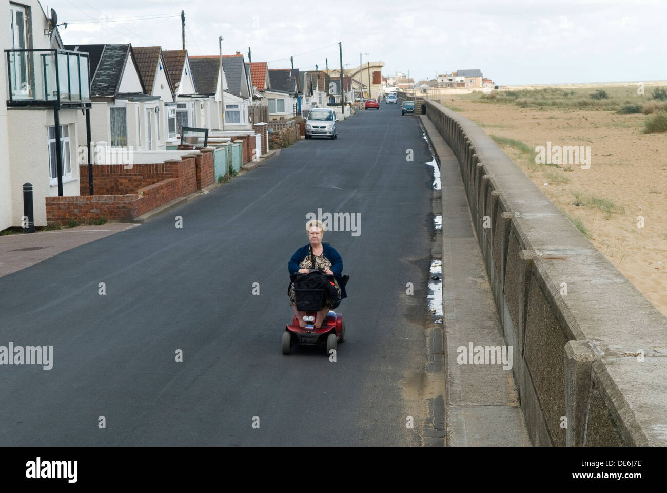 Pauvreté Royaume-Uni. Une femme âgée âgée handicapée conduisant son scooter motorisé de mobilité pour personnes handicapées Jaywick Essex UK. Brooklands Estate Senior oap pauvreté féminine dans une ville côtière. Années 2013 2010 Royaume-Uni HOMER SYKES Banque D'Images