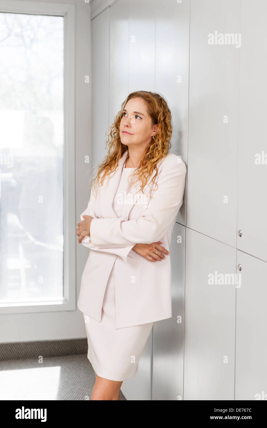 Thoughtful business woman standing in office corridor Banque D'Images