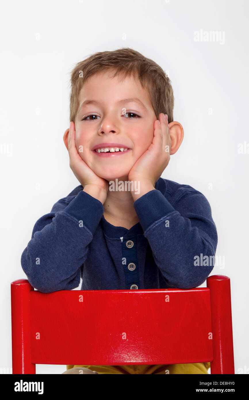 Portrait de garçon assis sur chaise rouge, smiling Banque D'Images