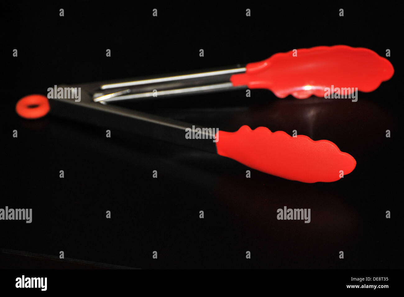 Une paire de langues cuisine silicone rouge avec une poignée en métal. Banque D'Images