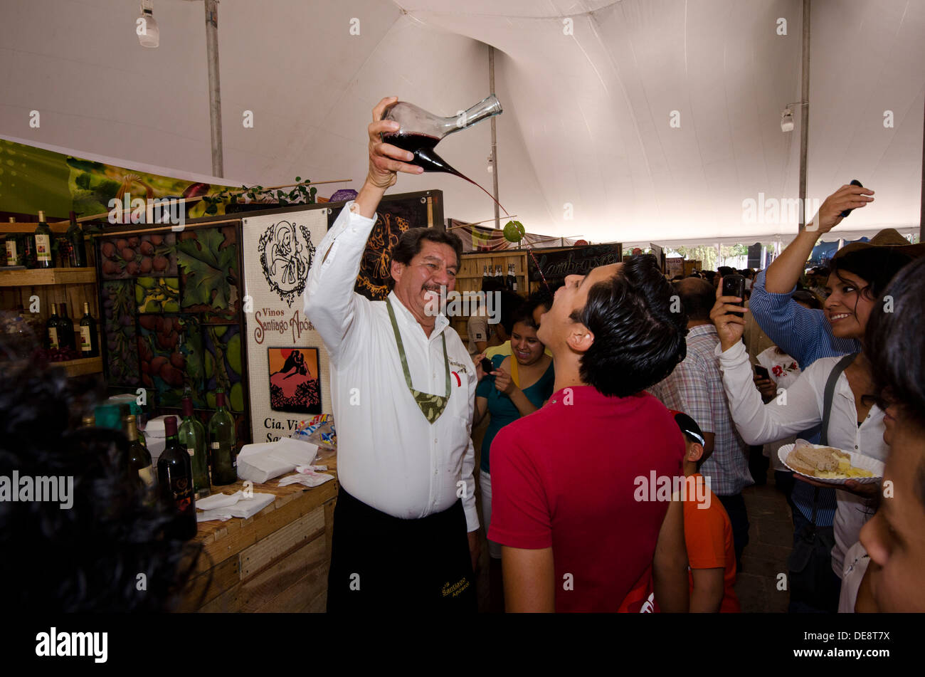 L'homme de verser le vin dans la bouche un autre homme au Festival National de fromage et de vin à Tequisquiapan, Queretero au Mexique Banque D'Images