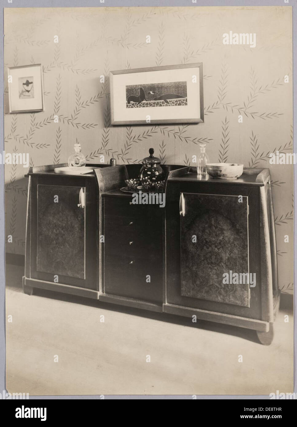 Le Dressoir, ou buffet, conçu dans les années 1920 et 1930, reflète l’accent mis par le Conseil des Arts sur le design fonctionnel et esthétique des meubles néerlandais. Caractérisé par ses lignes épurées et l'utilisation pratique de l'espace, le buffet illustre les tendances de design d'intérieur moderne de l'époque et reste une pièce classique dans l'histoire de l'ameublement néerlandais. Banque D'Images