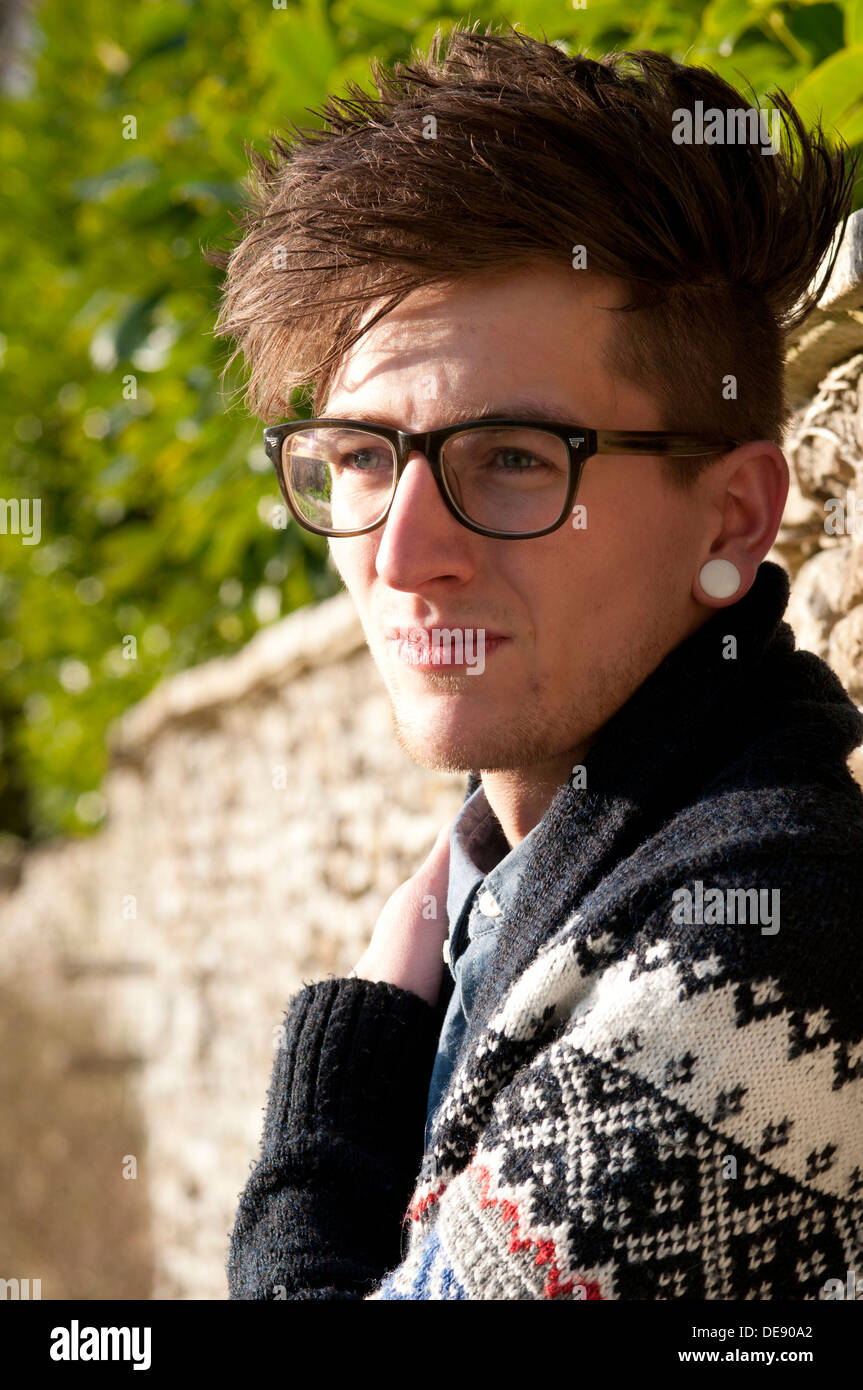 Portrait de jeune homme à l'extérieur portant des lunettes et une boucle d' oreille Photo Stock - Alamy