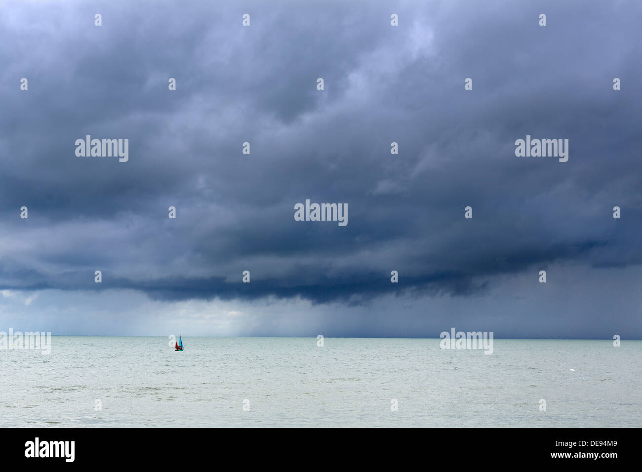 Petit canot voile vers une tempête au large de la côte de la station balnéaire de Aberaeron, Ceredigion, pays de Galles, Royaume-Uni Banque D'Images