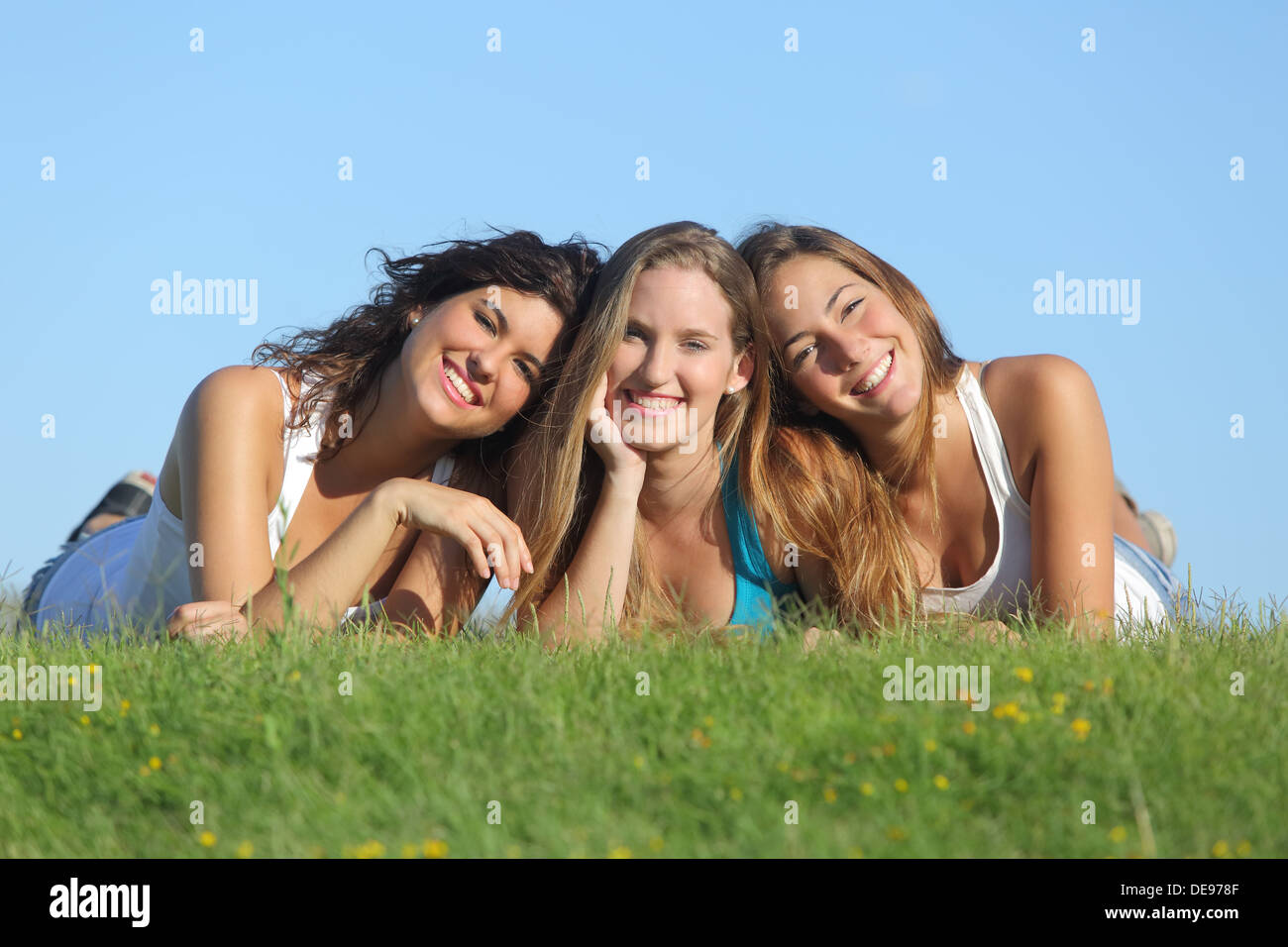 Portrait d'un groupe de trois professionnels adolescent girls smiling couché dans l'herbe avec le ciel en arrière-plan Banque D'Images