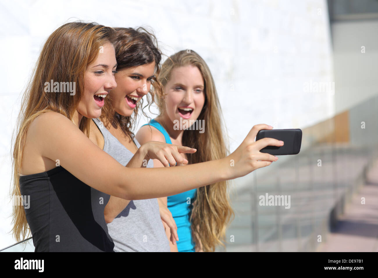 Groupe de trois adolescentes surpris à regarder le téléphone intelligent outdoor Banque D'Images