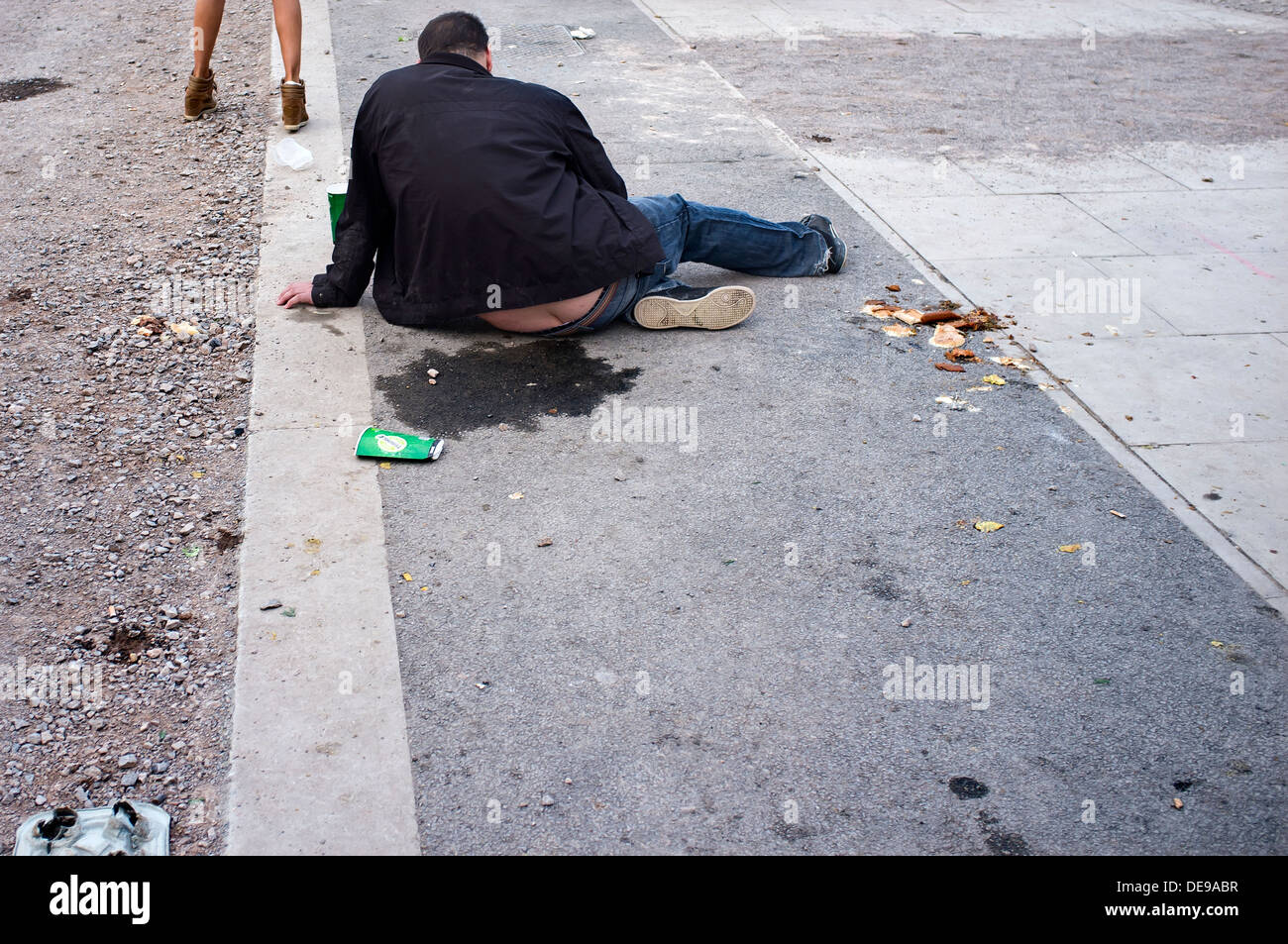 Drunk man sitting on pavement Banque D'Images