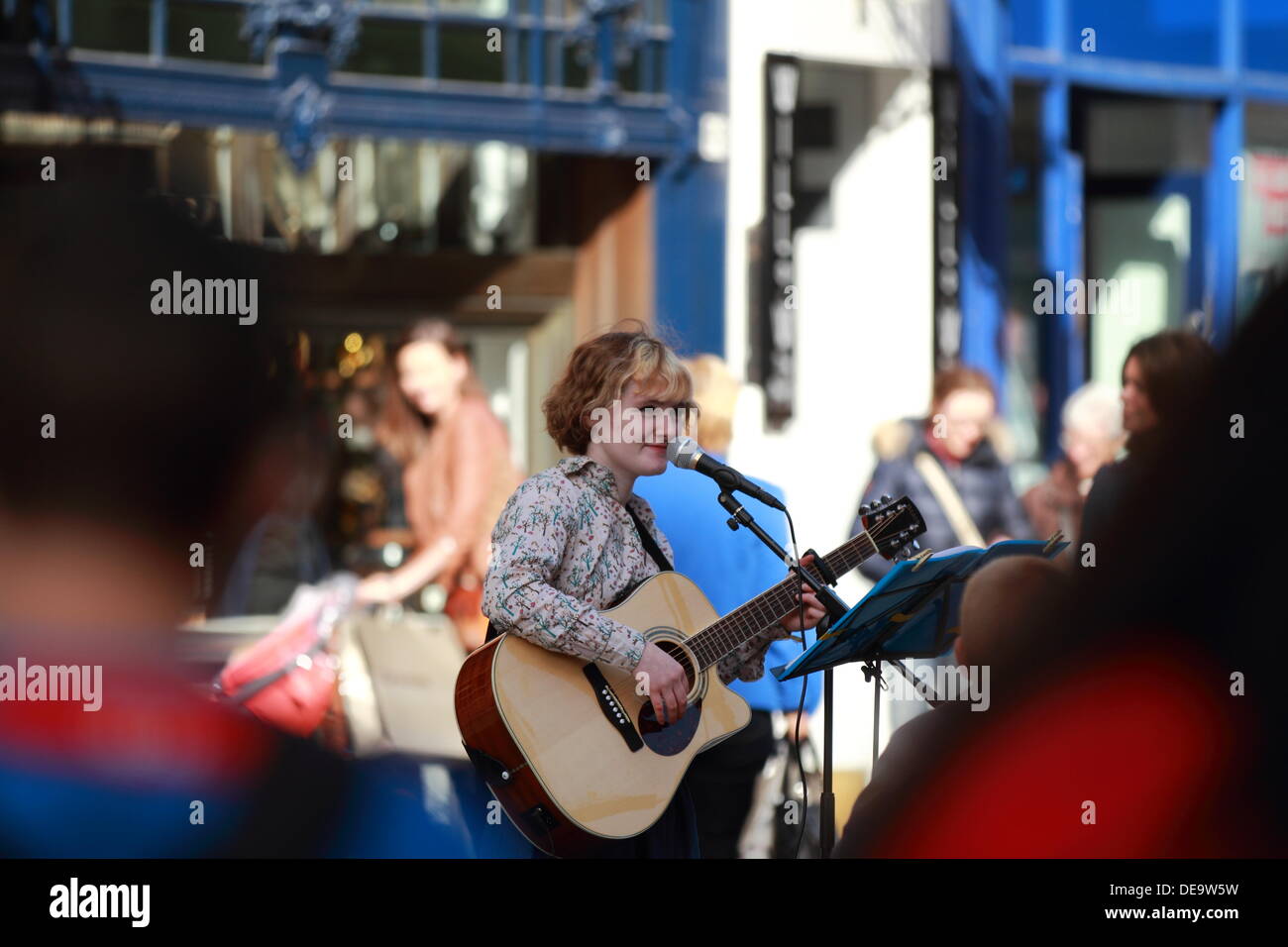 Jeune femme à la guitare acoustique joue busker la foule Dans Buchanan Street, Glasgow, Scotland, UK Banque D'Images