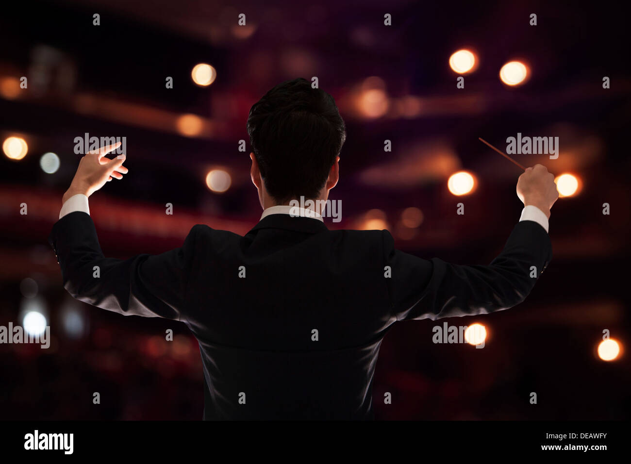 Jeune Chef avec baton soulevées à une performance, vue arrière Banque D'Images
