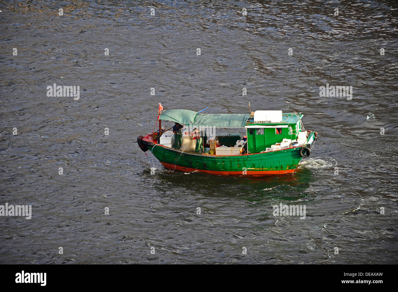 Petit bateau de pêche vert à l'œuvre dans le port de Hong Kong Banque D'Images