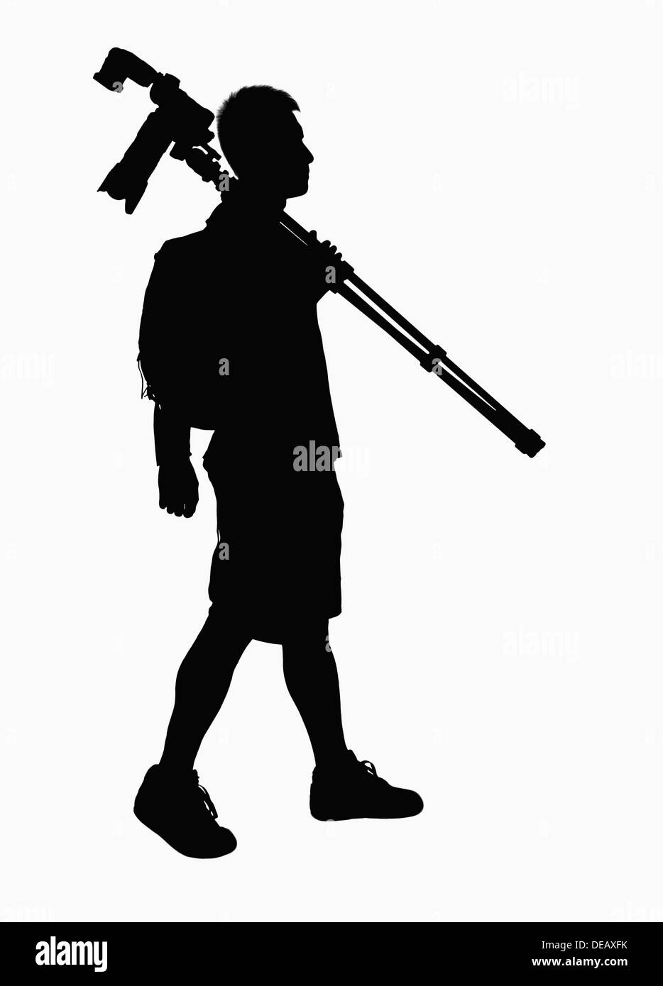 Silhouette of man carrying caméra et trépied. Banque D'Images