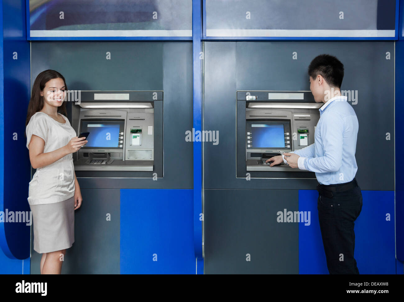 Deux personnes debout et de retrait de l'argent dans un distributeur Banque D'Images