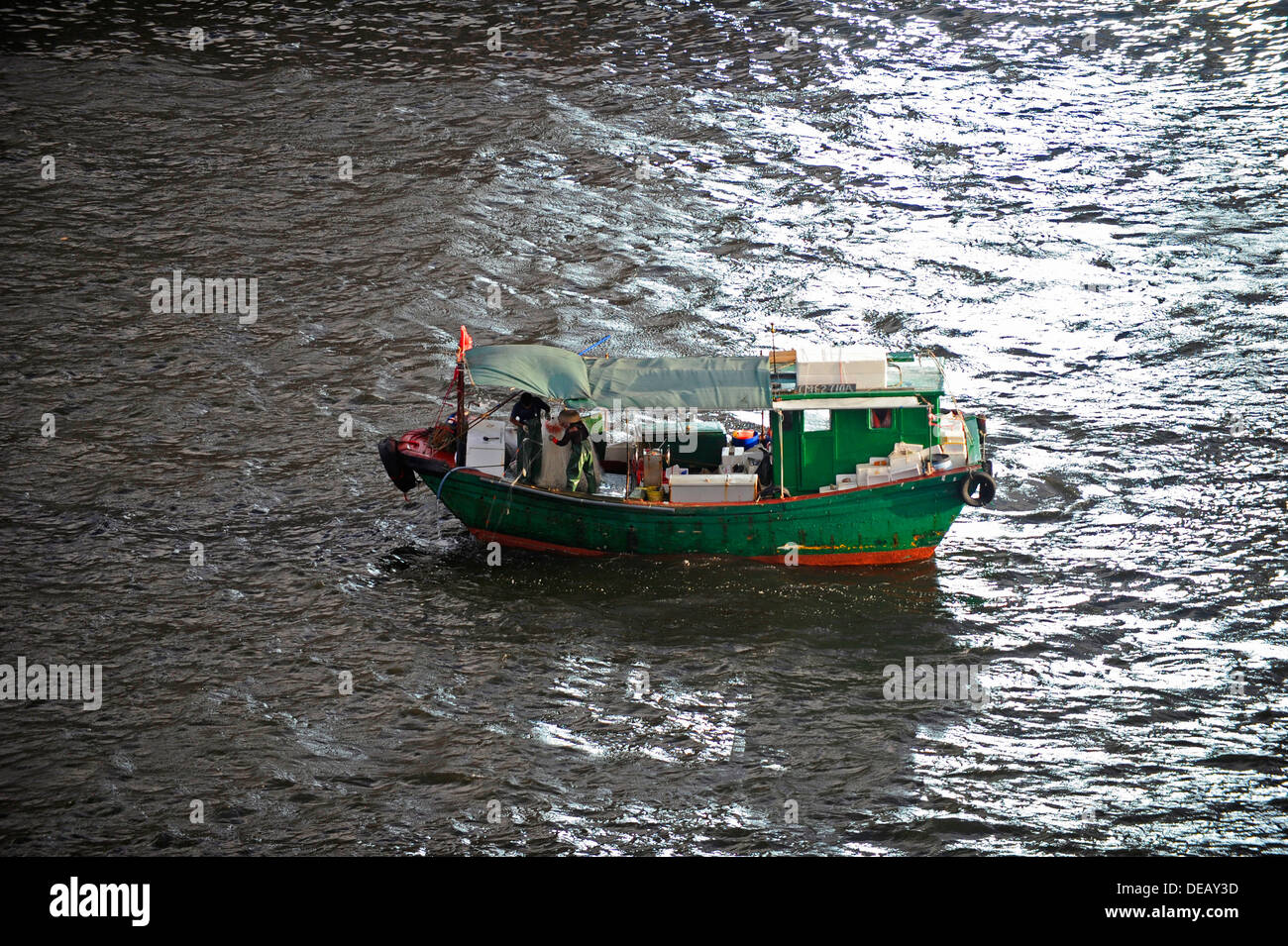 Petit bateau de pêche vert à l'œuvre dans le port de Hong Kong Banque D'Images