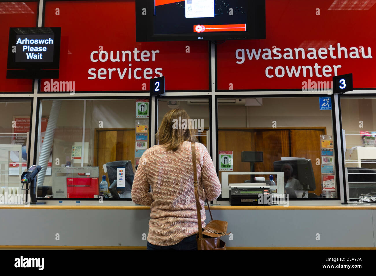 Client d'une femme au guichet d'un office de poste, au Pays de Galles UK Banque D'Images