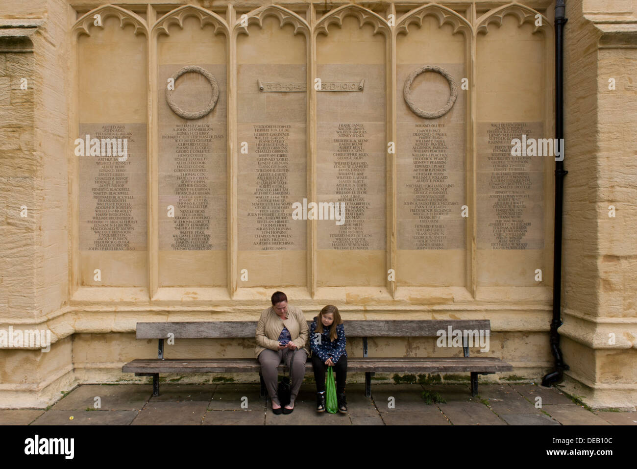Les habitants de Cirencester siéger au-dessous de la première guerre mondiale mémorial sur le mur de l'église dans le centre-ville. Banque D'Images