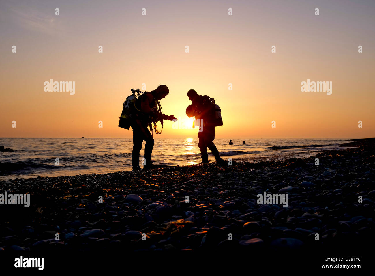 Deux hommes en silhouette, la plongée au coucher du soleil, la baie de Cardigan, Wales Aberystwyth UK Banque D'Images