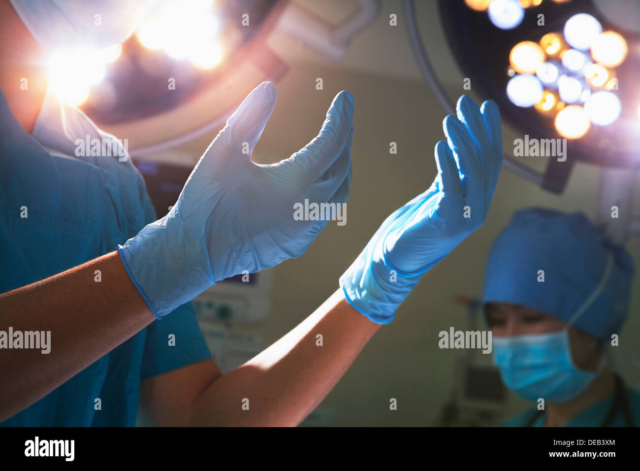 Au milieu de la vue dans les mains des gants chirurgicaux et feux chirurgicale en salle d'opération Banque D'Images