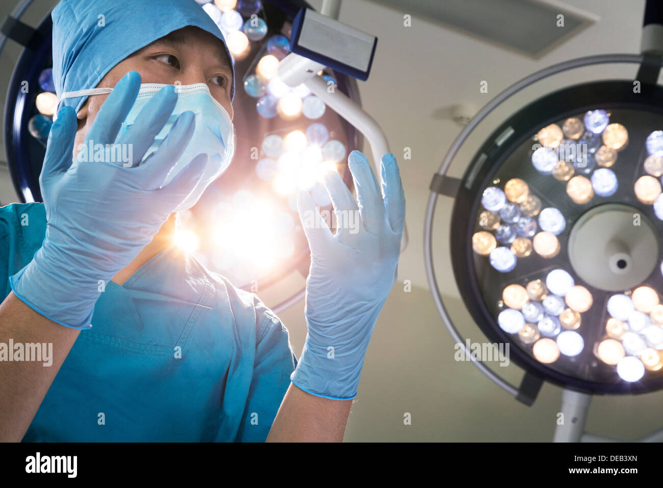 Low angle view of surgeon holding les mains gantées avec feux chirurgicale derrière lui Banque D'Images