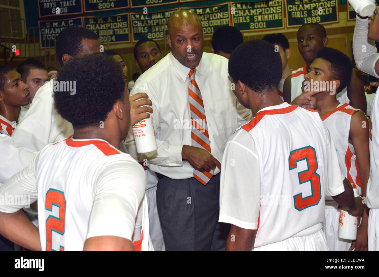 Coach discuter stratégie avec son équipe dans un match de basket-ball de l'école secondaire. Banque D'Images