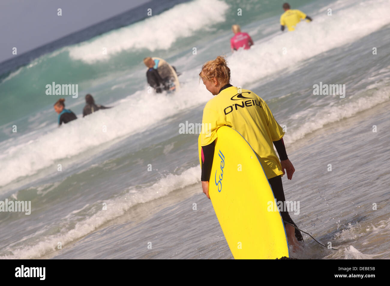 Les femmes avec surf board apprendre à surfer à l'école de surf à Sennen Cove Cornwall Banque D'Images