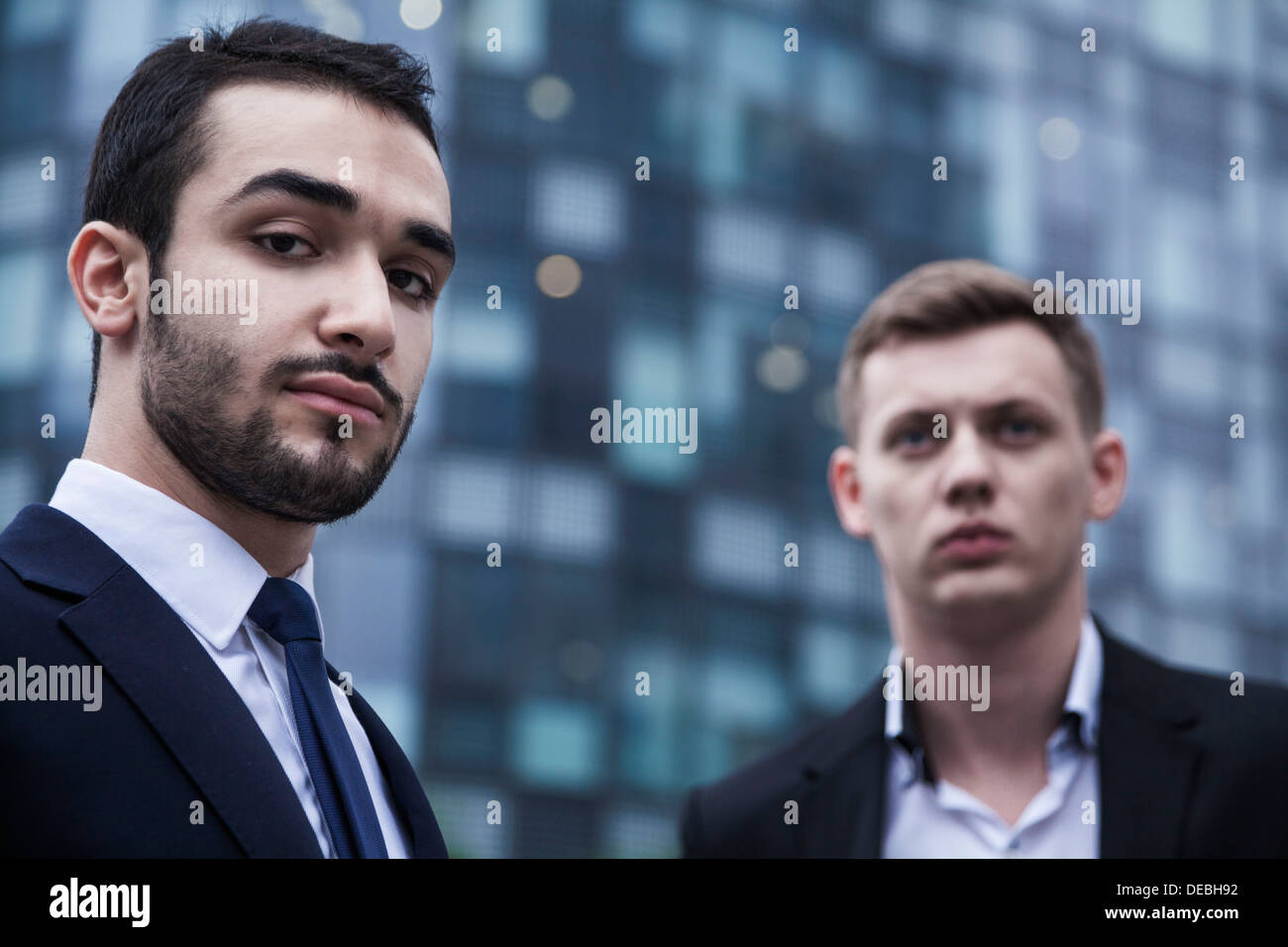 Portrait de deux jeunes hommes d'affaires sérieux regardant la caméra, à l'extérieur, le quartier des affaires Banque D'Images