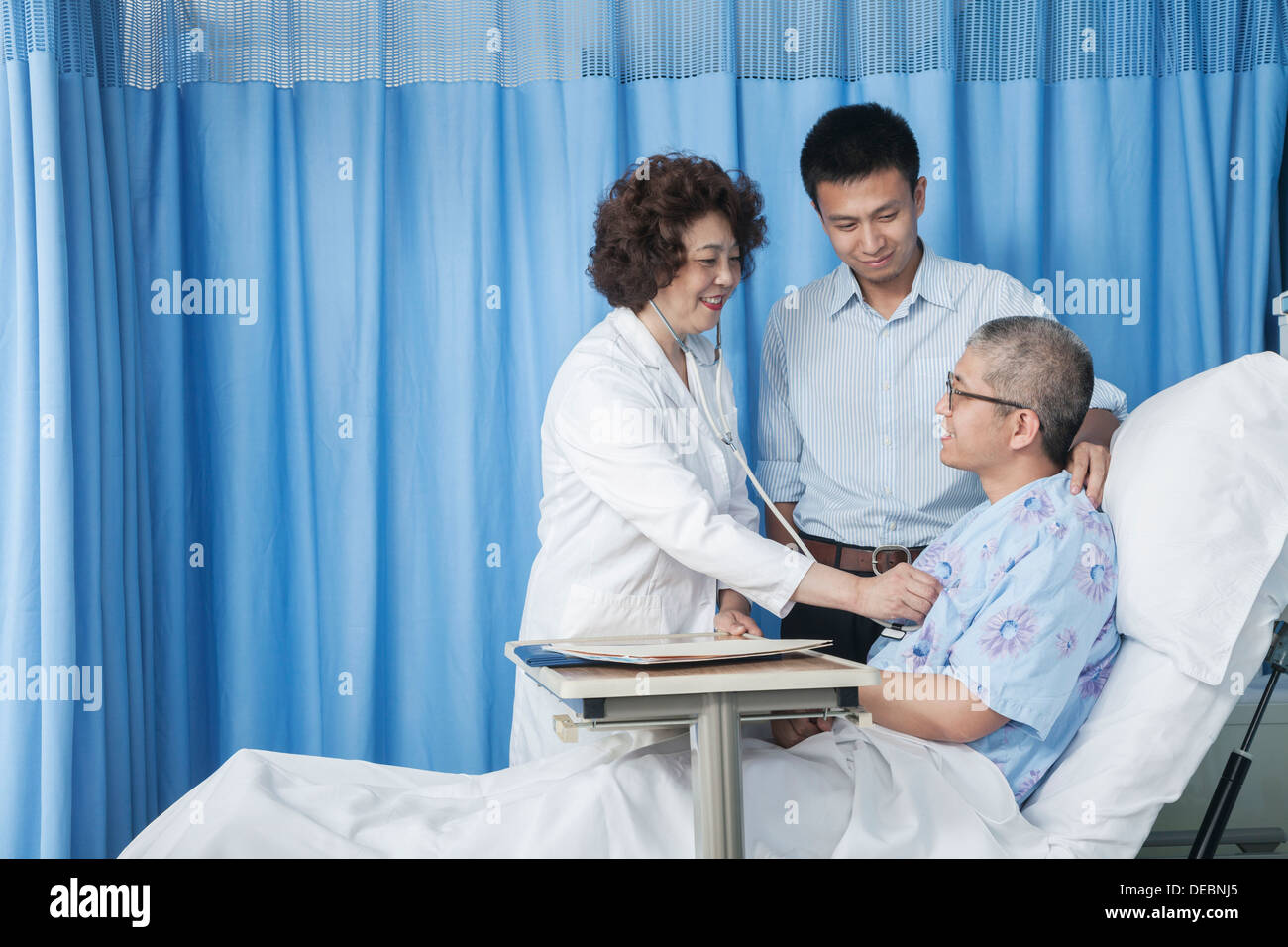 Médecin contrôle des patient qui est couché dans le lit avec son fils  adulte à ses côtés Photo Stock - Alamy