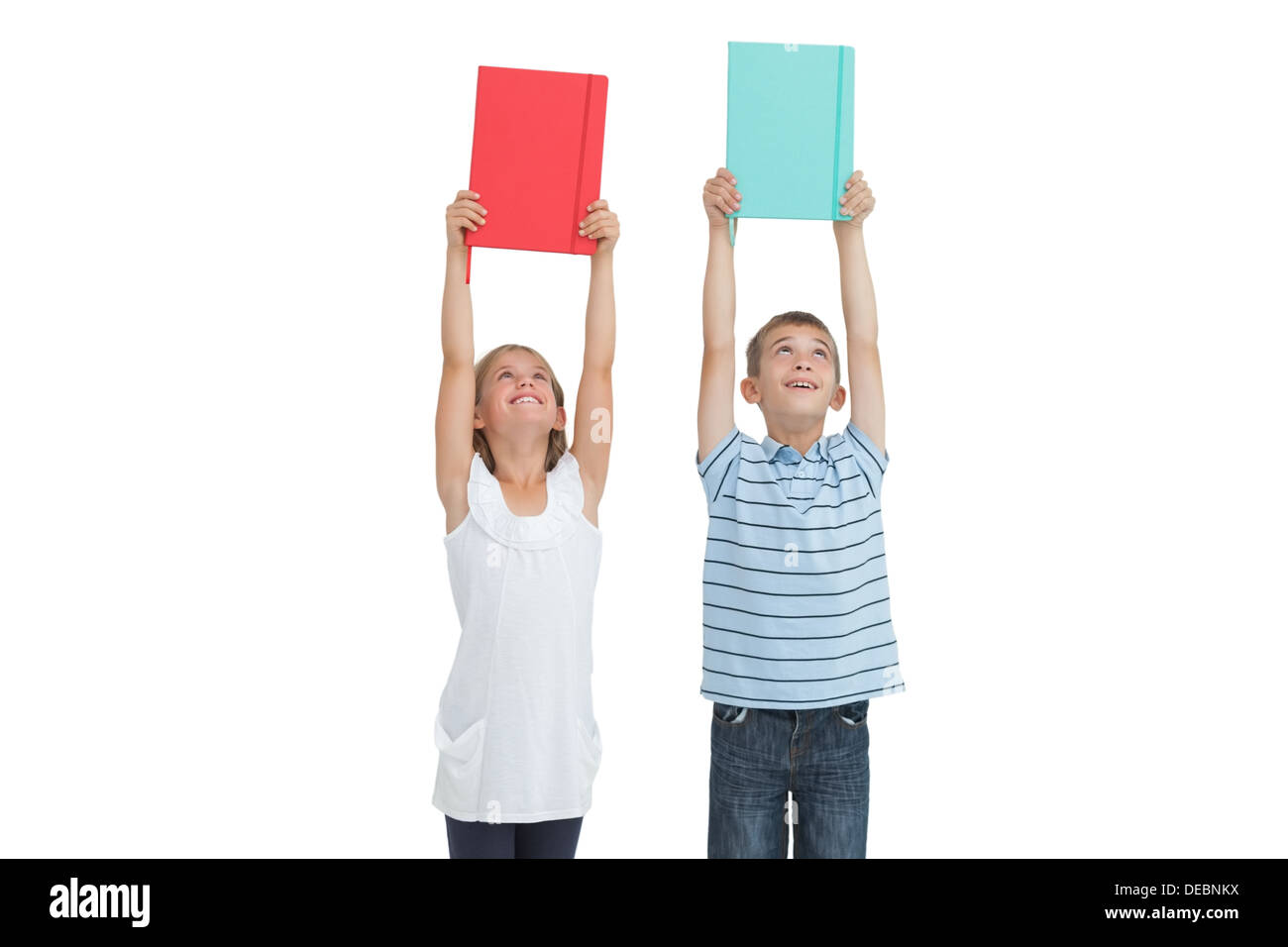 Smiling brother and sister holding their notebooks au-dessus de leur tête Banque D'Images