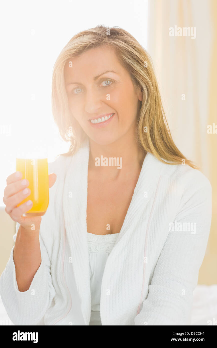 Content woman looking at camera bénéficiant d''un verre de jus d'orange Banque D'Images