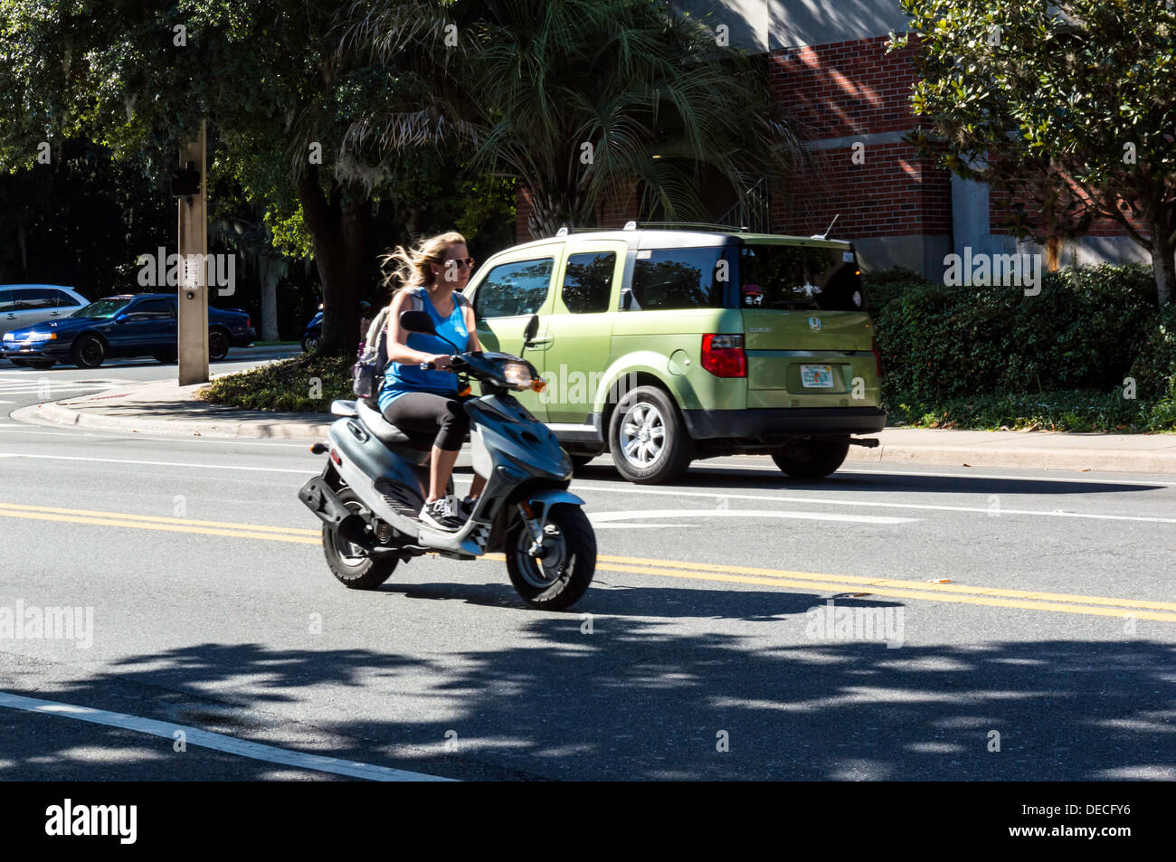 Jeune fille femme avec de longs cheveux blonds circonscription cyclomoteur scooter de gaz on city street. Banque D'Images