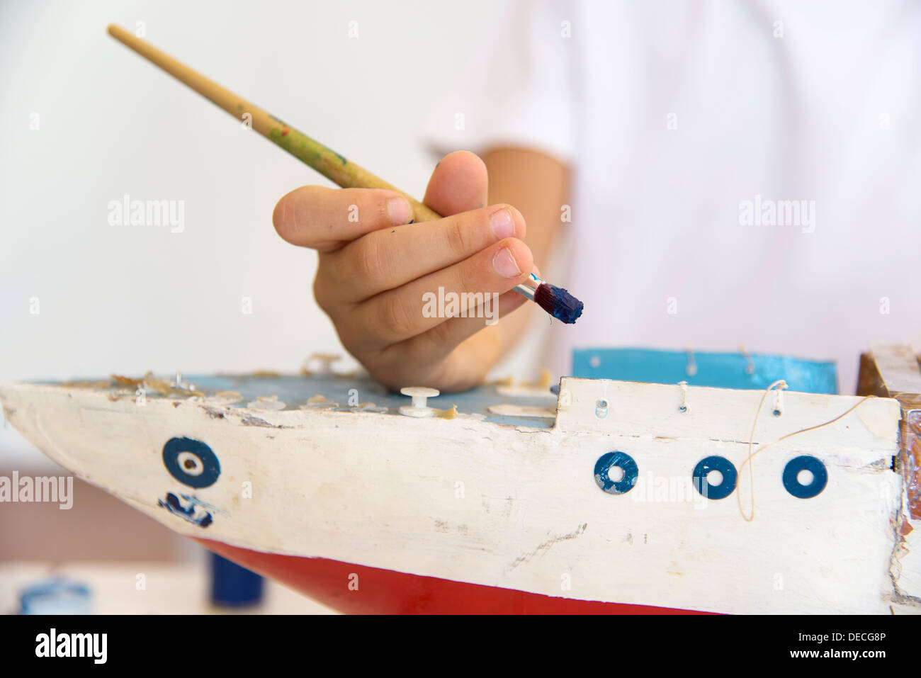La peinture de l'enfant ancien bateau en bois avec un pinceau Banque D'Images